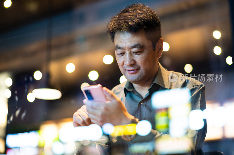 亚洲中年男子在咖啡店使用智能手机