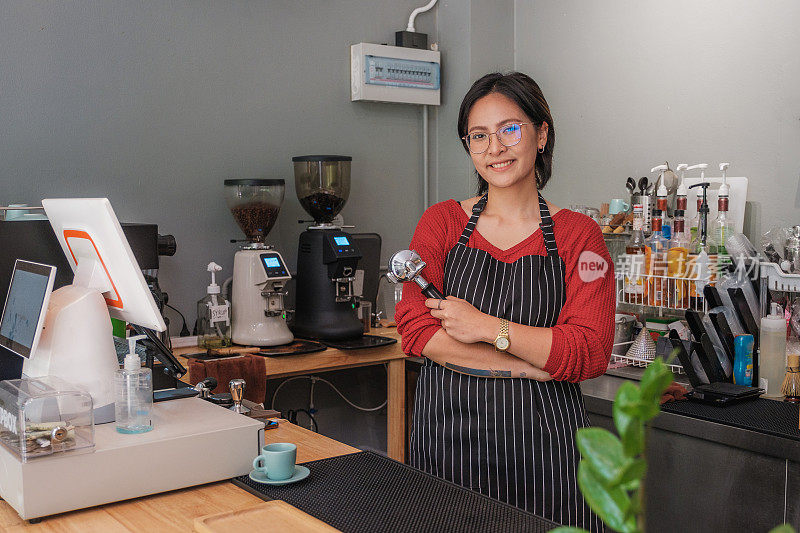 年轻的亚洲女性咖啡师或咖啡店老板站在咖啡店的柜台