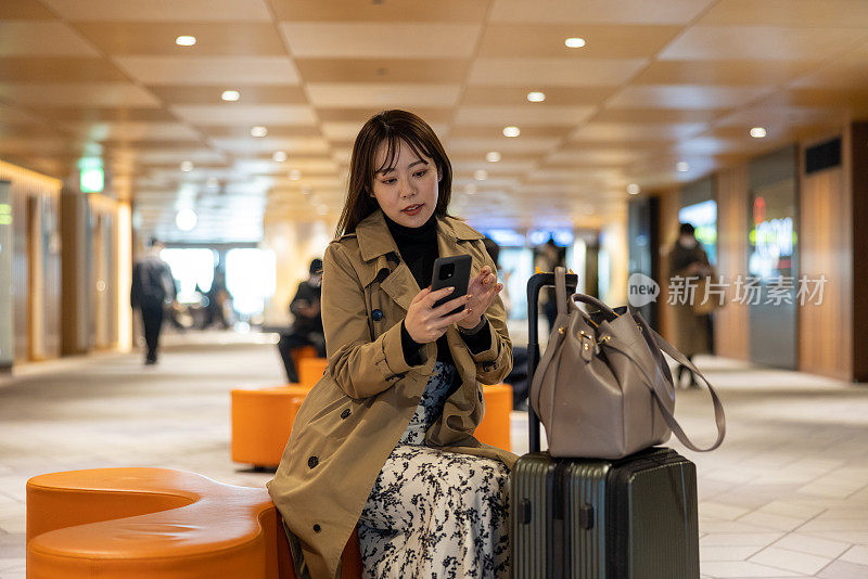 亚洲女商人在机场航站楼使用智能手机