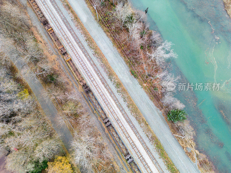 火车轨道和道路运行沿着清澈的蓝色冰川河植被Arial照片