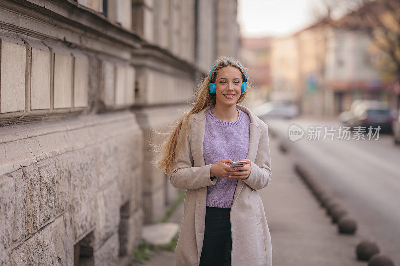 年轻自信的女人在街上听音乐的肖像