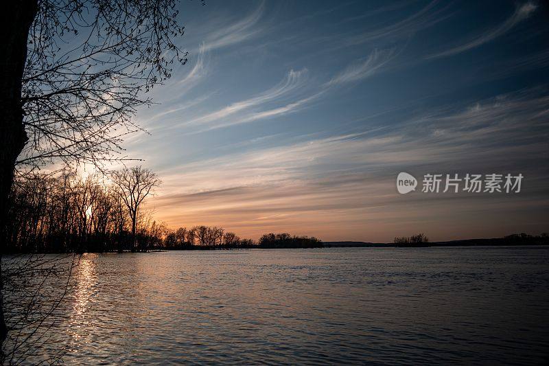 夏日夕阳下的风景，湖泊被树木环绕，太阳在水面上的倒影
