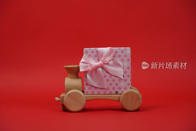 红色背景的汽车木制玩具和礼品盒。