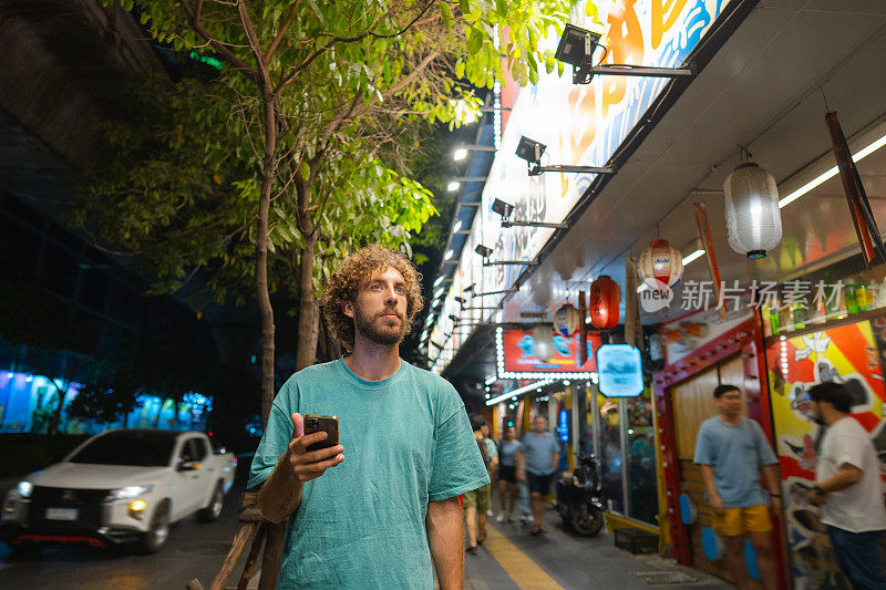 一名男子拿着智能手机走在东京的夜晚