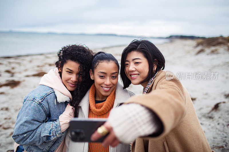 三个年轻女子在海滩上自拍