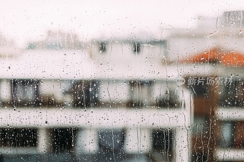 雨滴打在窗玻璃上，背景是建筑物