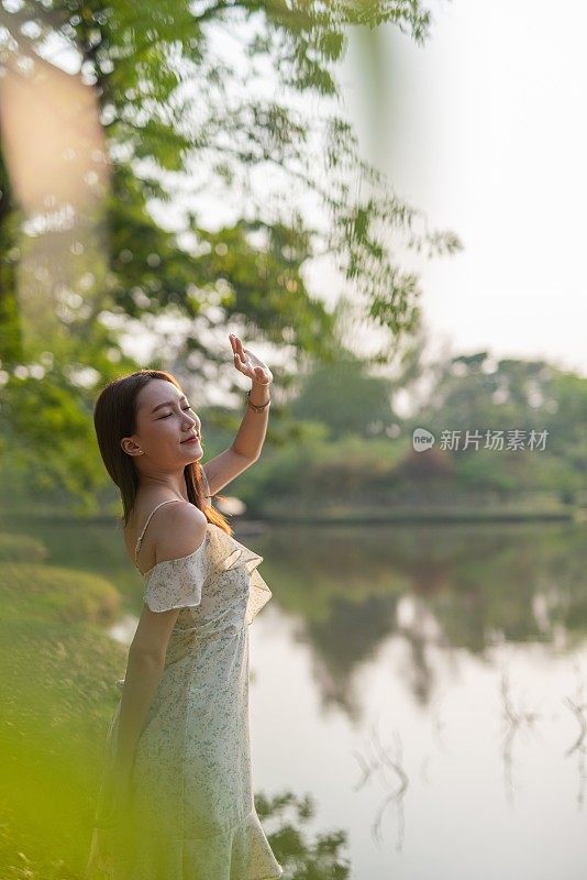 年轻美丽的亚洲女人徘徊在一个郁郁葱葱的绿色公园。