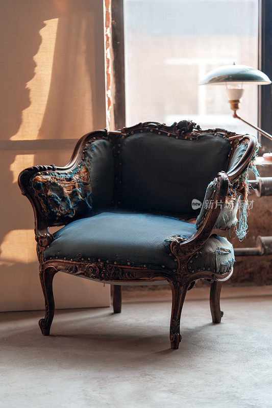 经典复古扶手椅与美丽的雕刻木制元素和蓝色撕裂室内装饰在垃圾房间与绿色的灯在窗台上。