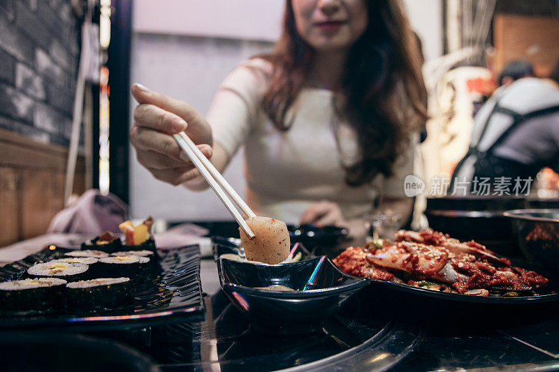 在日本大阪观光的一位亚洲女性正在大阪鹤桥地区品尝当地的韩国料理。