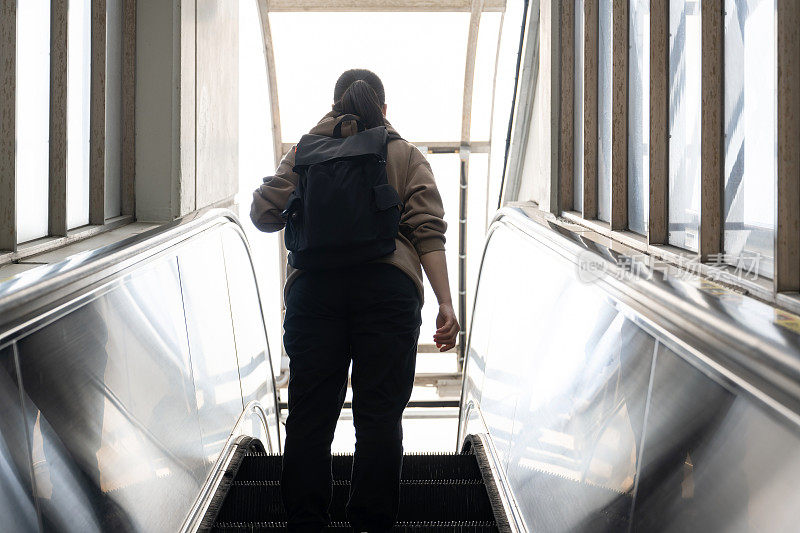 一位女游客正在乘坐公共自动扶梯