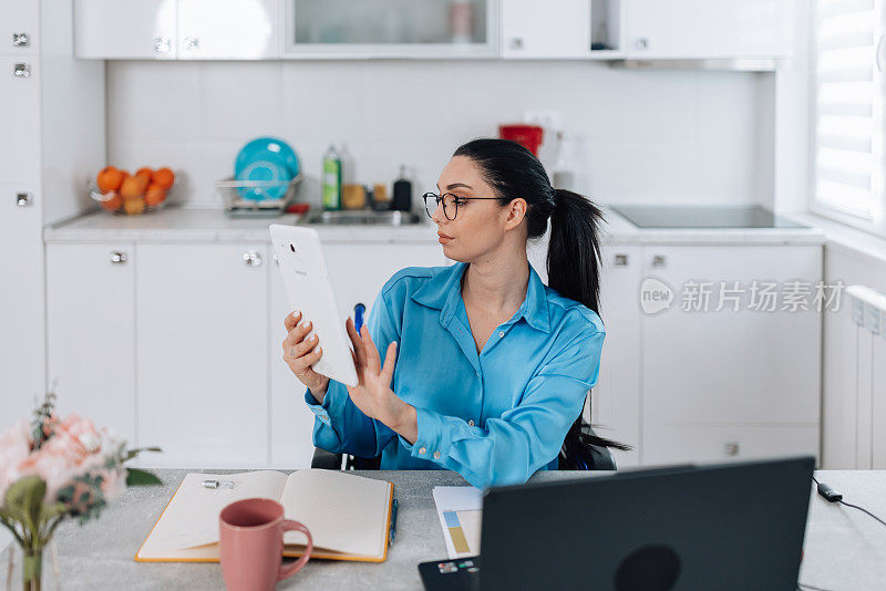 坐在轮椅上的年轻女子无缝地使用数码平板电脑和笔记本电脑