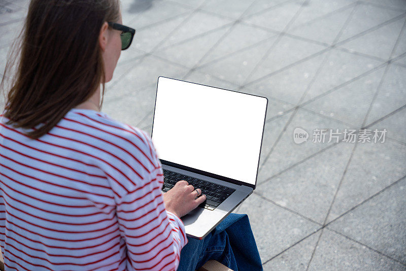 一名年轻女子在户外使用一台白屏笔记本电脑。笔记本电脑屏幕模型