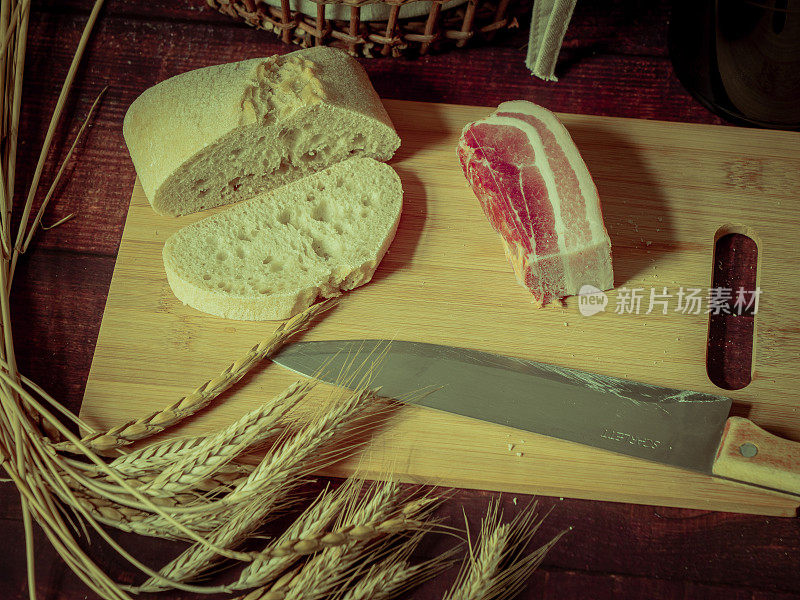 古风质朴的静物画配上面包、麦穗、火腿和培根。