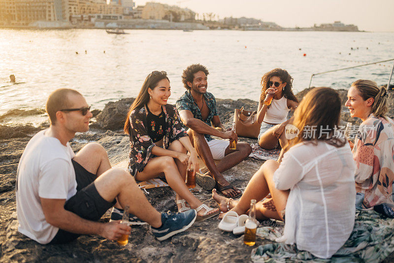 一群形形色色的人聚集在海滩上闲逛。他们随意聊天，喝啤酒，享受他们在一起的时光