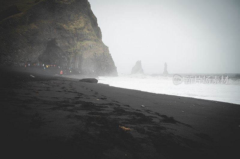 黑沙滩Reynisfjara与许多游客在远处，多雾的天气，冰岛
