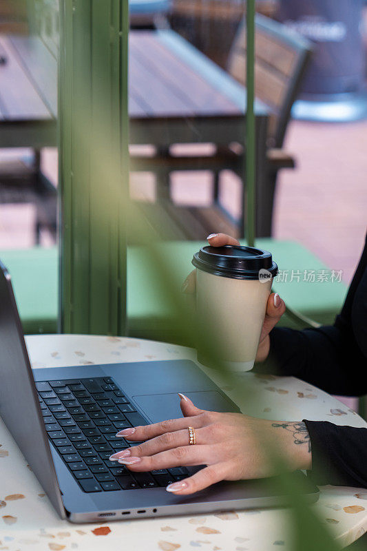 一个女孩在咖啡馆里端着咖啡在电脑前工作。