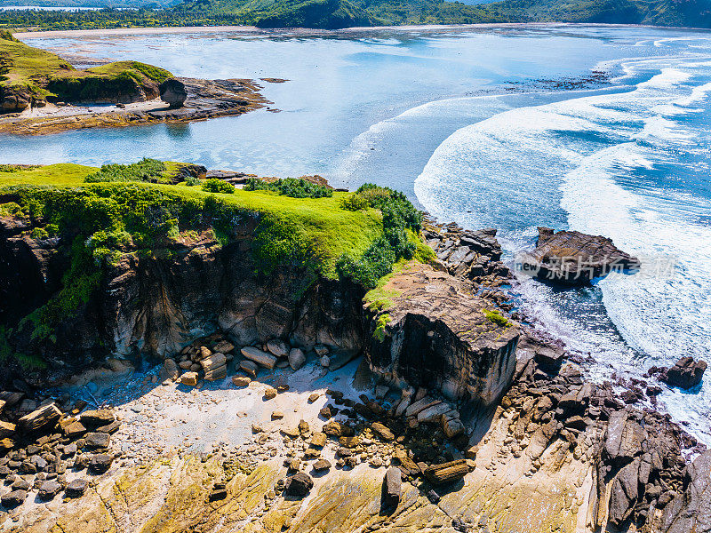 绿色海岸悬崖、岩石海岸线和蓝色海浪的鸟瞰图。Lombok岛。