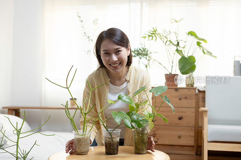 年轻的亚洲女性带着用回收塑料瓶制成的盆栽微笑的肖像。把塑料瓶或废料回收到花盆里。回收再利用的概念。