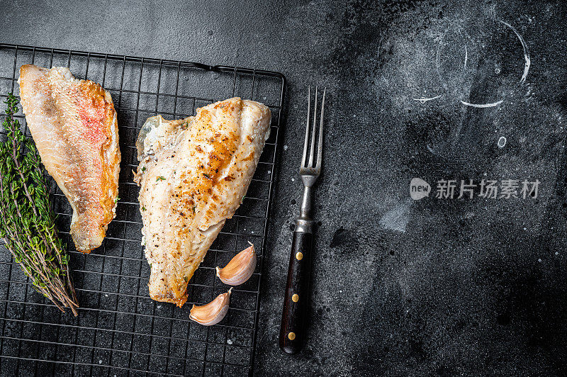烤海红鲈鱼片，鲷鱼架。黑色背景。前视图。本空间