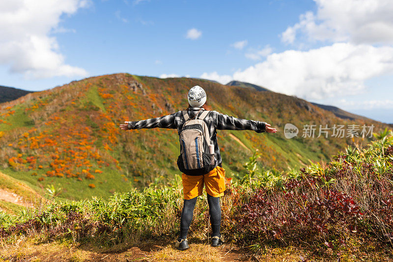 一位女性徒步旅行者停下来欣赏秋天的山景