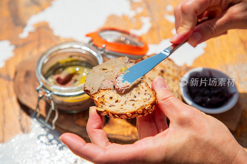 鹅肝酱用餐刀抹在一片全麦面包上