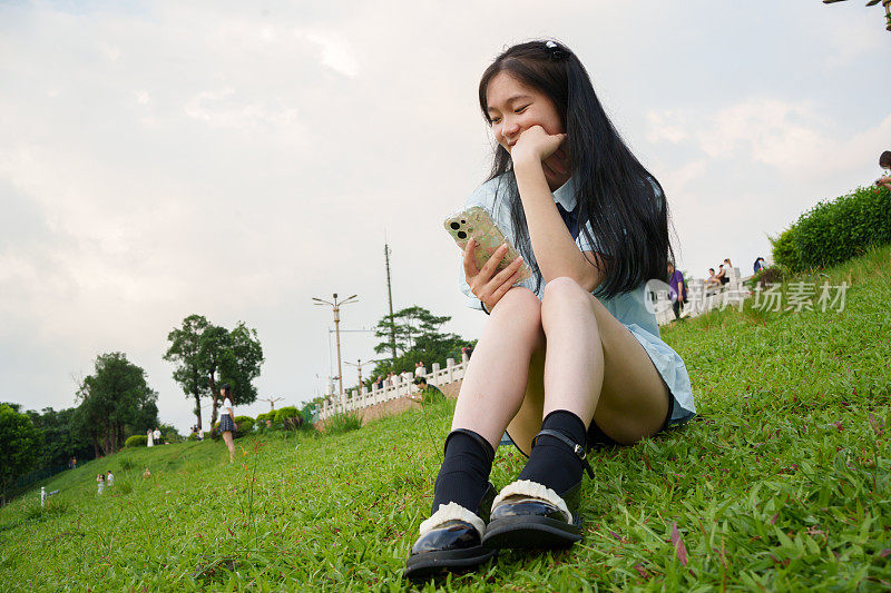 女孩坐在草地上看手机