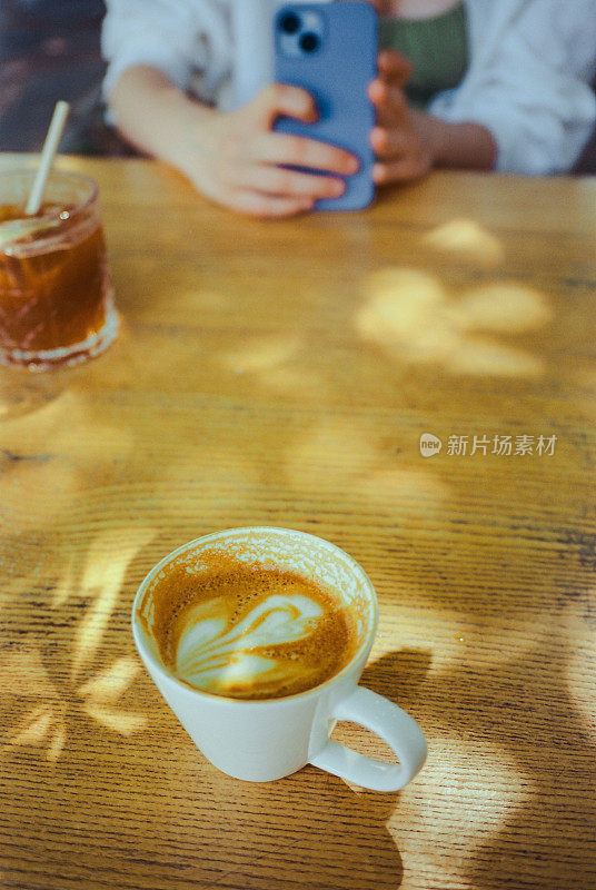 一杯咖啡和一个女人在早午餐时用智能手机拍照