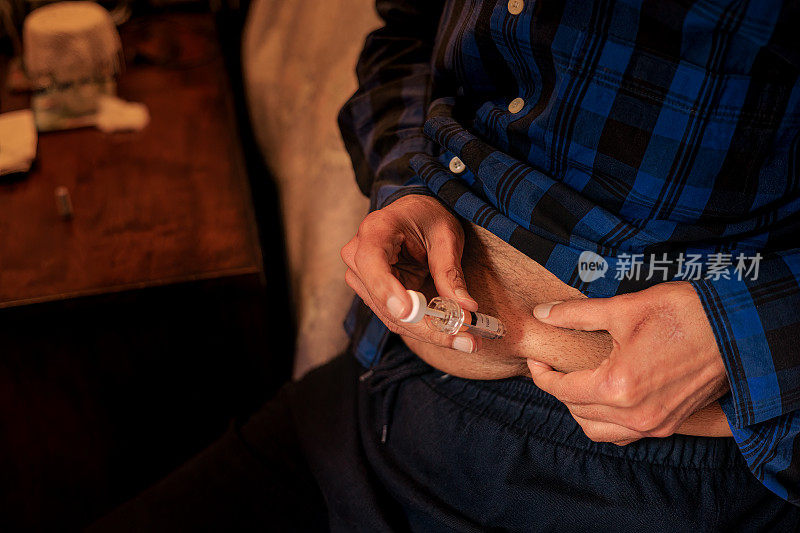 一名76岁的亚洲男子在腹部手术后准备用预先填充的皮下注射器给自己注射处方药。