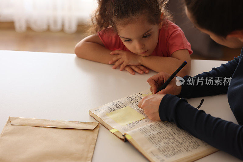 女人在不干胶便条纸上记笔记，小女孩看着她