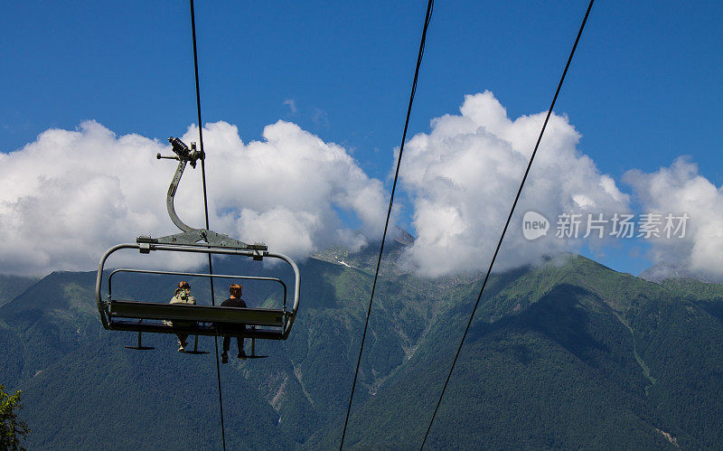 游客们乘坐缆车的悬椅穿梭在青山之间