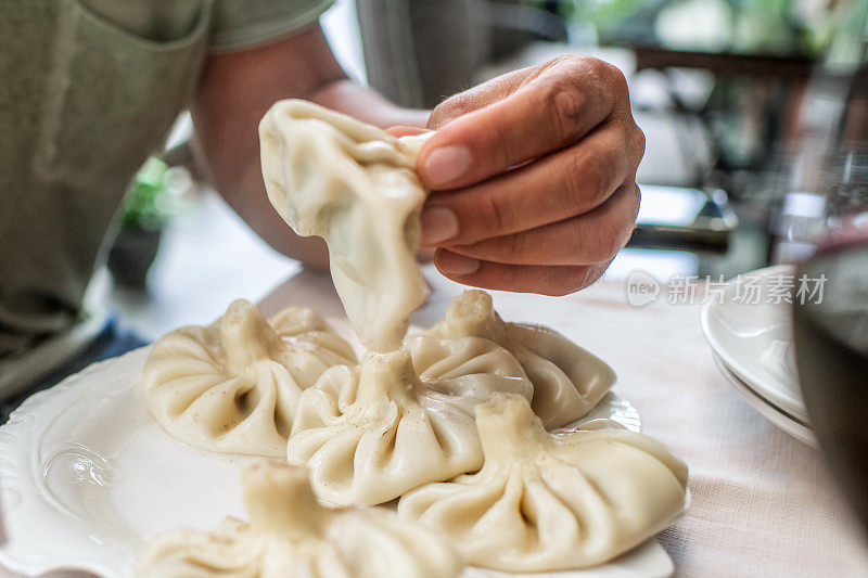 格鲁吉亚传统美食。一名男子正在吃Khinkali——美味的饺子，里面有肉、香草和香料。