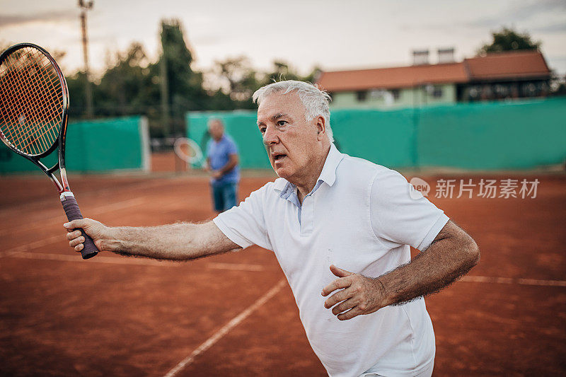 两个活跃的老人在室外网球场打网球双打