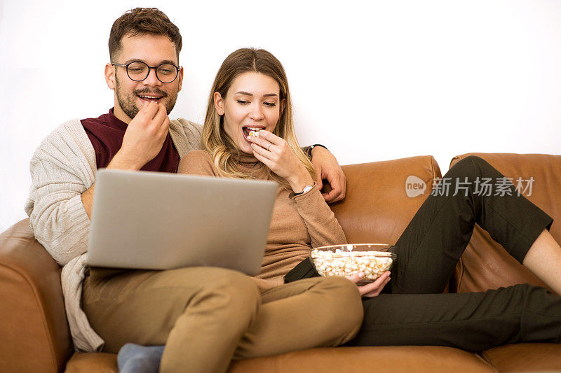 一对年轻夫妇在家里用笔记本电脑看电影