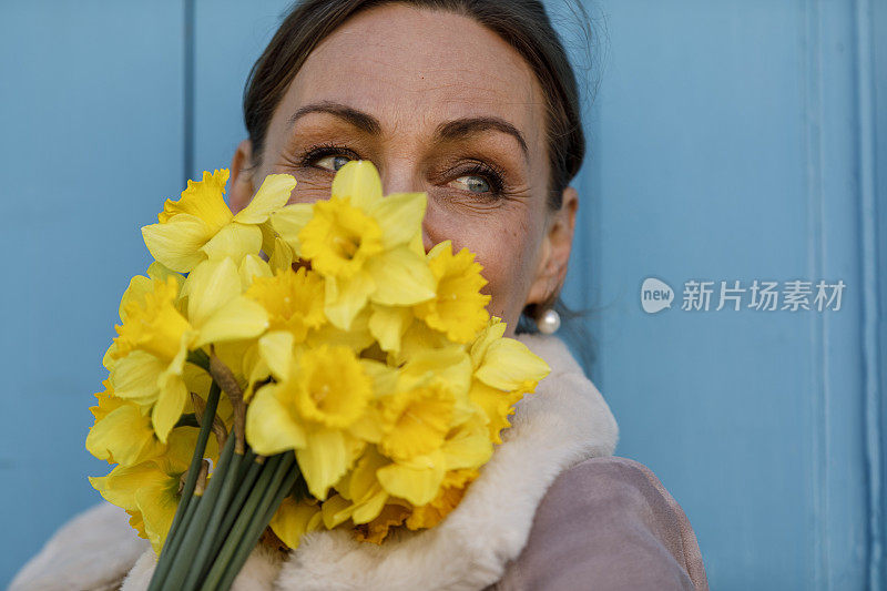 快乐成熟的女人闻着水仙花，沉思着