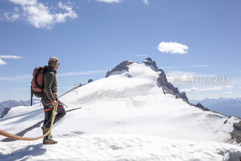 一位男性登山运动员到达了雪山的顶峰