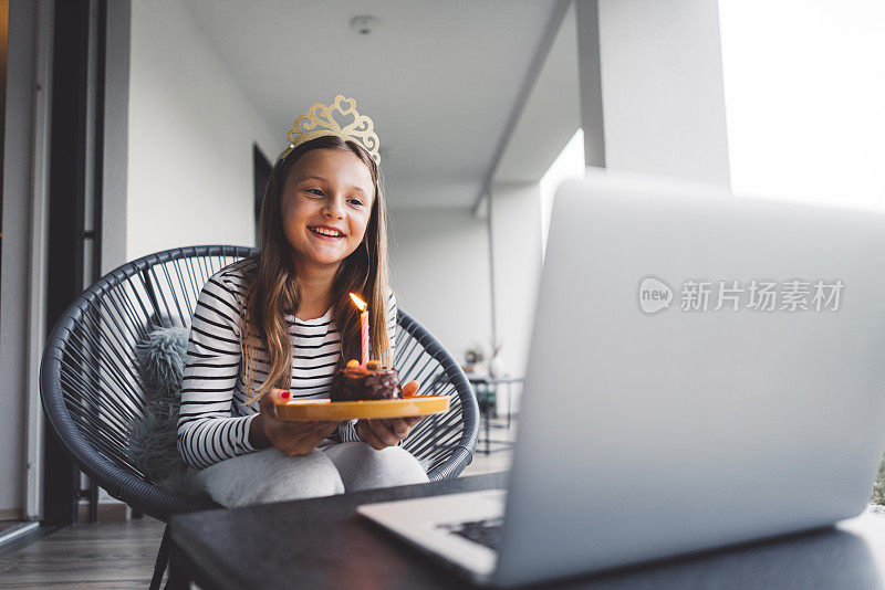 一个小女孩拿着一个生日蛋糕和祖父母在视频电话上庆祝她的生日