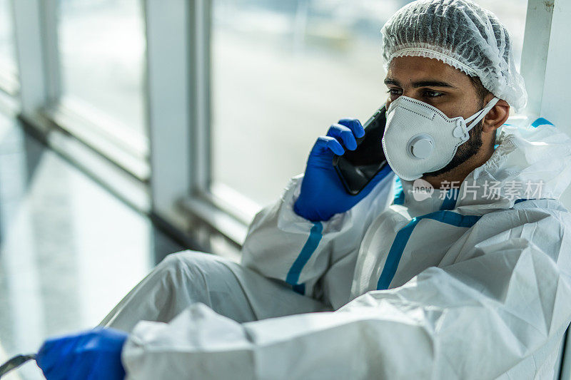 冠状病毒疫情的爆发。疲惫的印度医生在医院与呼吸器在干净的西装和手机
