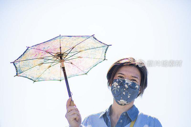 一个带着面具和阳伞的女人