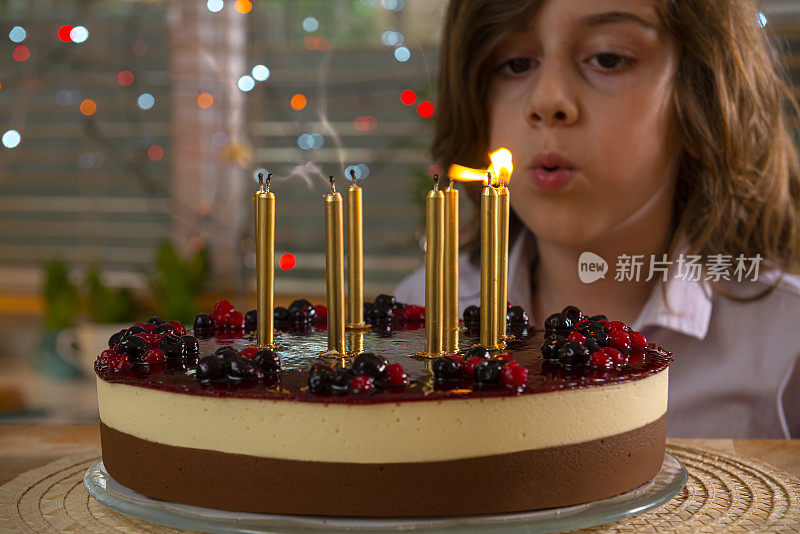 一个男孩吹灭生日蛋糕上的蜡烛。