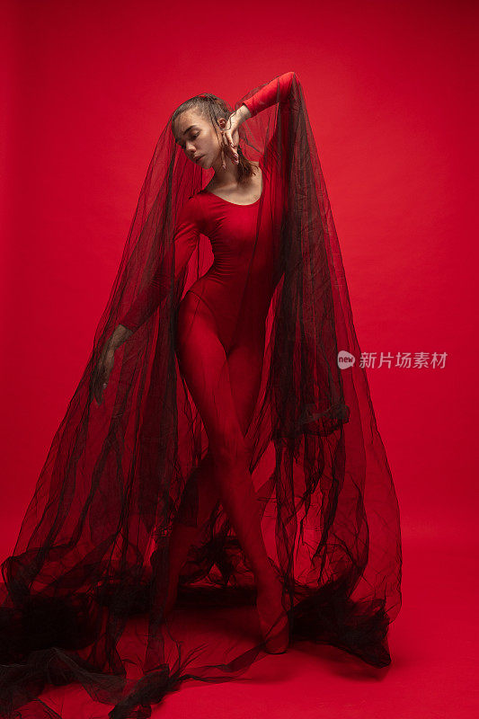 年轻美丽的女孩的肖像，女芭蕾舞者训练孤立在红色的背景。