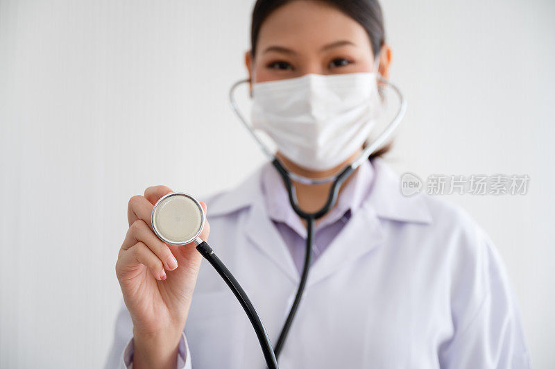 冠状病毒爆发期间，一名戴着面罩的女医生手持心率监测器站在实验室里。预防新冠肺炎疫情传播理念。