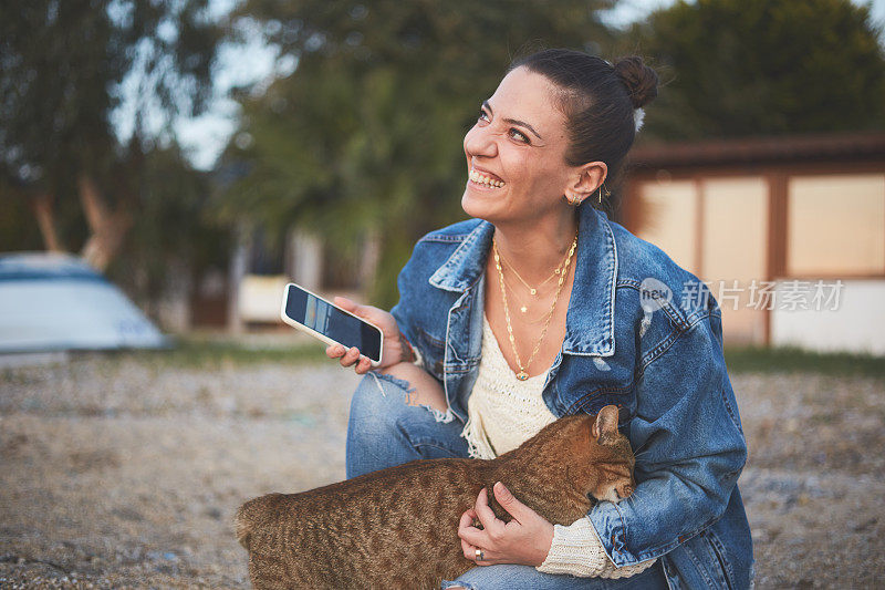 微笑快乐的女人喜欢海滩上的猫