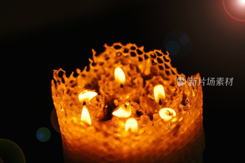 一只大的蜂蜡蜡烛在黑色的背景上，七支小的蜂蜡蜡烛合二为一的俯视图，火正在燃烧
火焰传播。耶路撒冷圣墓神庙的圣火