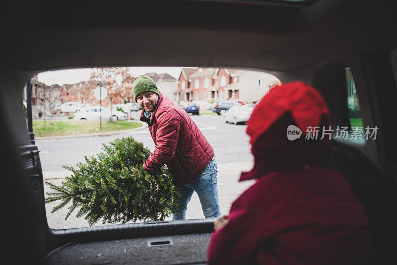 爸爸正在把圣诞树装进汽车后备箱