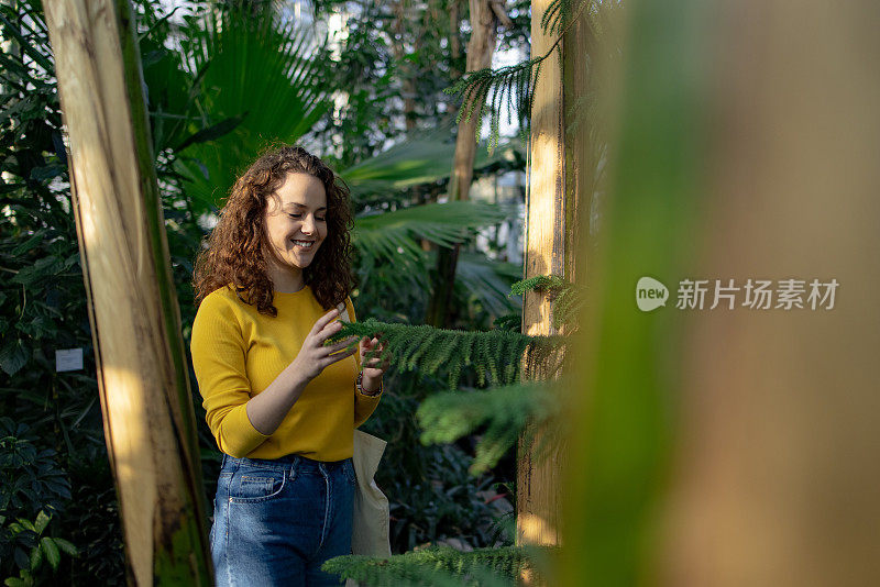 一个年轻的白人妇女在植物园里玩得很开心