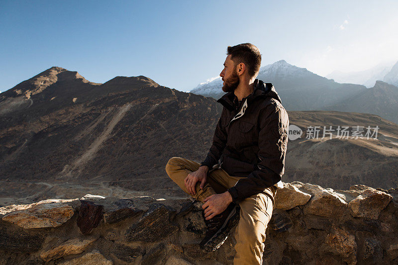 一个白人男子看着夕阳下的喜马拉雅山山谷