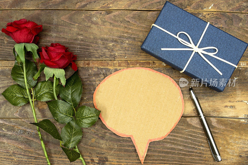 情人节或女性节的红玫瑰花，母亲节的空聊天气泡纸盒卡片和蓝色礼盒，木桌上的笔