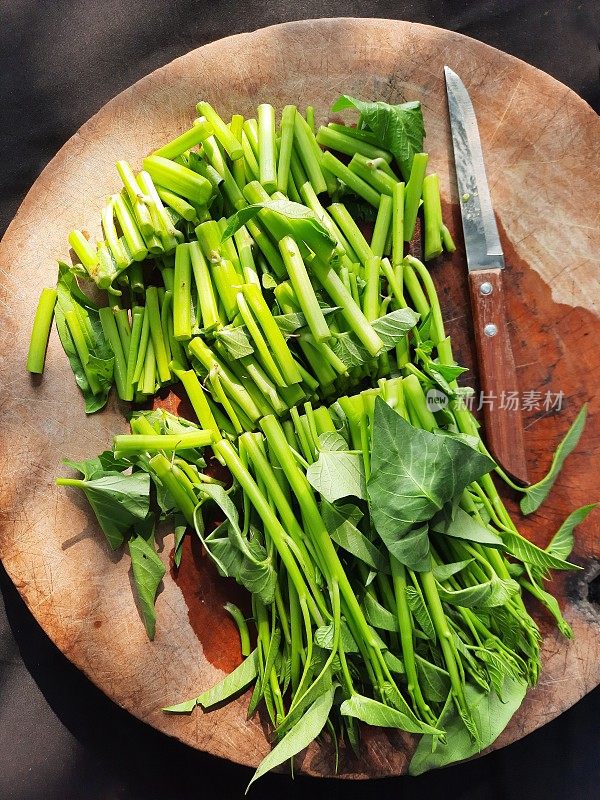 在切菜板上切牵牛花蔬菜-准备食物。