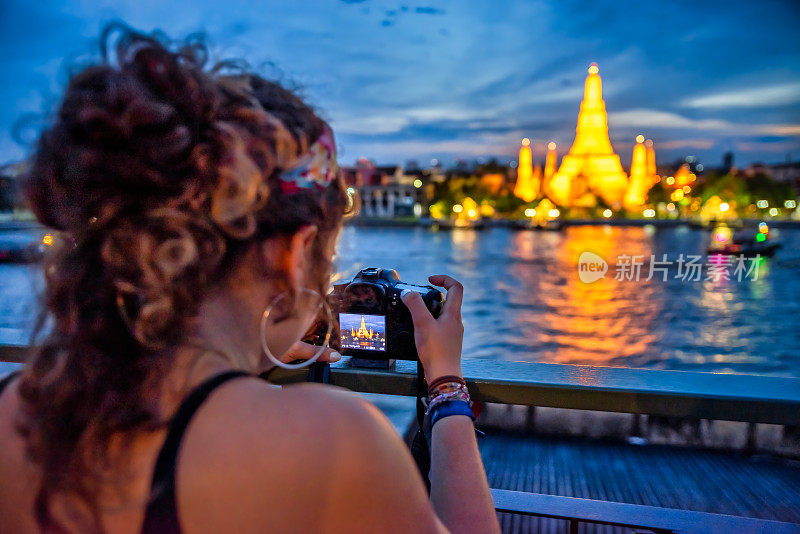 曼谷，一名女子在晚上拍阿伦寺的照片。泰国