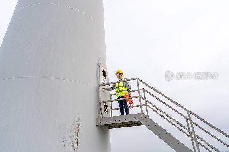 一名亚洲女工人正在爬风力涡轮机的梯子